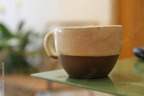 Εκτύπωση καμβά Ceramic coffee cup with two-tone glaze on green table in cafe setting