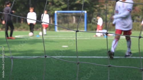 사람 축구 선수 스포츠 훈련 코트 야외 일상 소품 디테일 자재: 야외 인조잔디구장 골대 그물망 초점에 맞춰 뒤편에서 유소년 선수들이 훈련하는 모습을 담은 아웃포커스 동영상 클립입니다.
