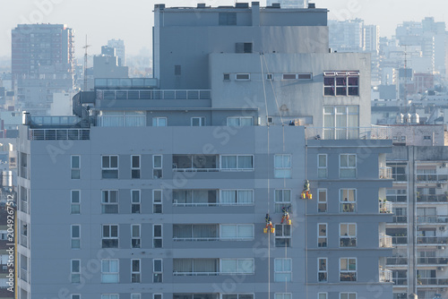 Craftsmen and painters work suspended from safety ropes on the facade of a high-rise residential building in Buenos Aires, Argentina