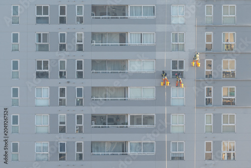 Craftsmen and painters work suspended from safety ropes on the facade of a high-rise residential building in Buenos Aires, Argentina