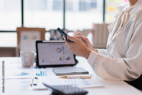 Photography Businesswoman using mobile phone with laptop computer on office table