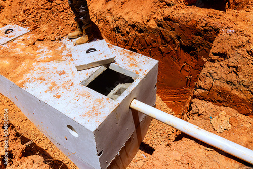 Fényképezés Workers install concrete septic tank into trench at construction site ground is dry with some dirt, rocks