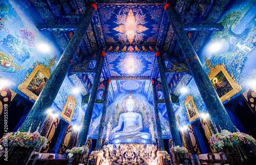 Inside Wat Rong Suea Ten Blue Temple Chiang Rai Thailand Buddha Statue. Spectacular interior view of Wat Rong Suea Ten with large white Buddha statue and intricate blue murals in Chiang Rai, Thailand.