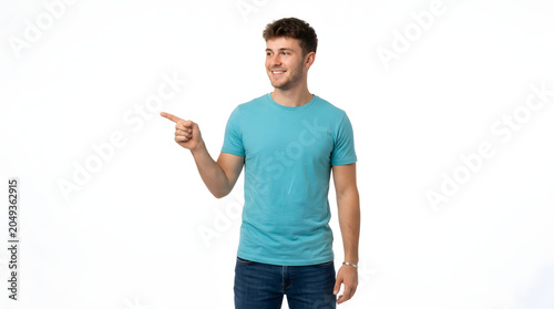 Young man in a blue t-shirt and jeans pointing to the left with a smile, looking to the side PNG Isolated on transparent background