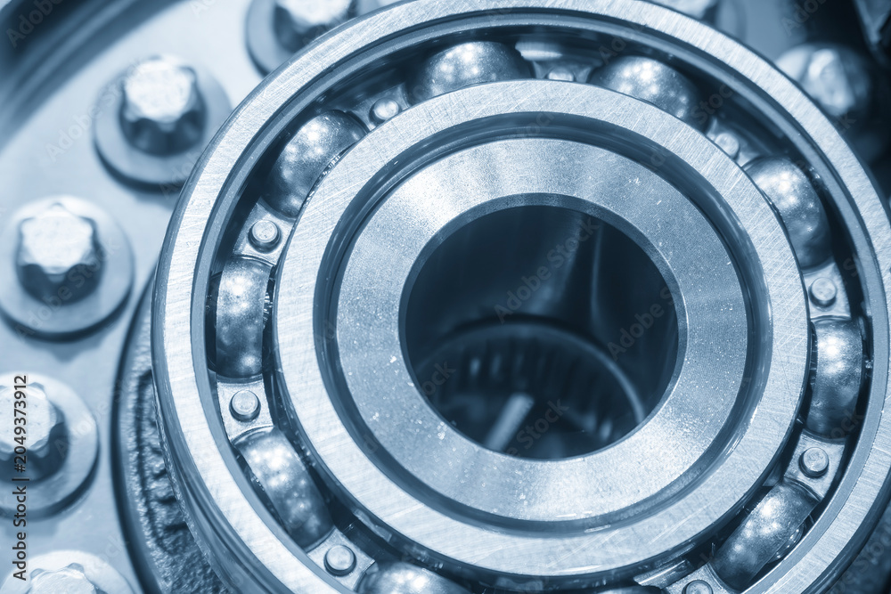 Obraz premium Close-up of a high-precision rolling bearing assembly process within an automotive part in a blue-toned scene.