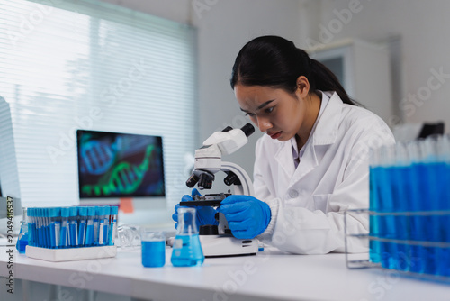 Female scientist researching dna molecules using a microscope