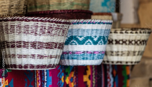 Vibrant woven baskets on display at market stall with colorful fabrics