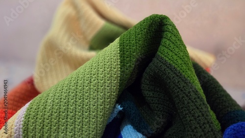 Close-up of folded green crochet fabric with detailed handmade stitches and soft texture, ideal for textile, craft, and home decor themes
