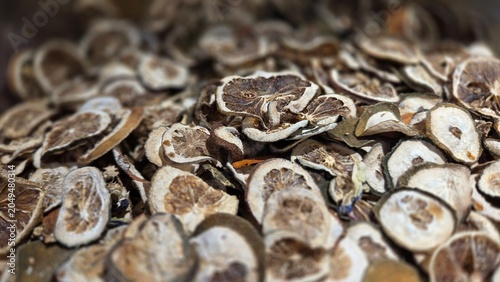 Close-up of dried lime slices in Indonesian market. Citrus herbal ingredient for tea, cooking, and traditional remedies. Natural texture background