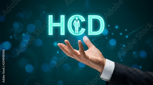 A businessman's outstretched hand offers glowing neon text HCD with a silhouette of a person inside the C human centered design human centered design thinking innovation concept