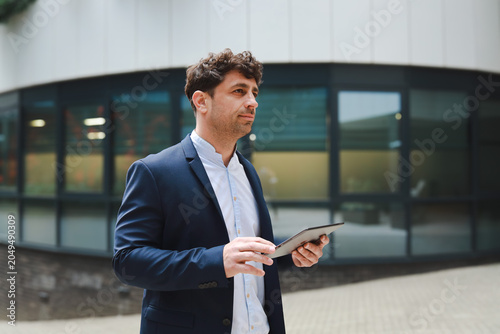 Business man using digital tablet outside office building