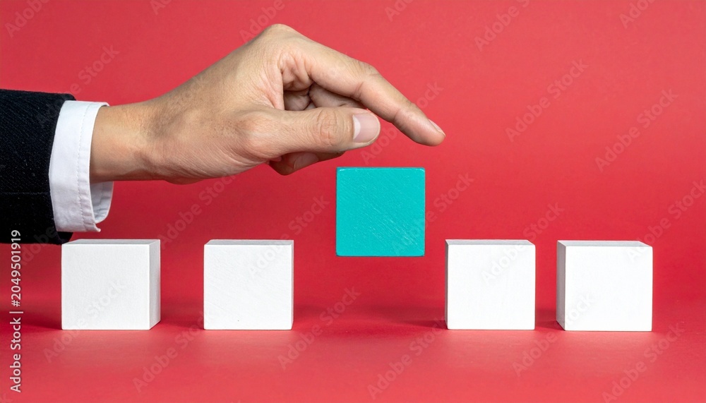 Obraz premium Hand holding blue cube above white cubes on red background