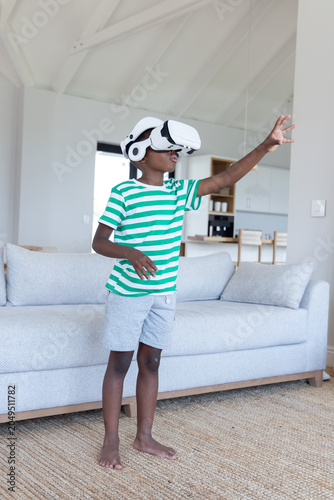 Photography African American child boy wearing white VR headset reaching forward in living r