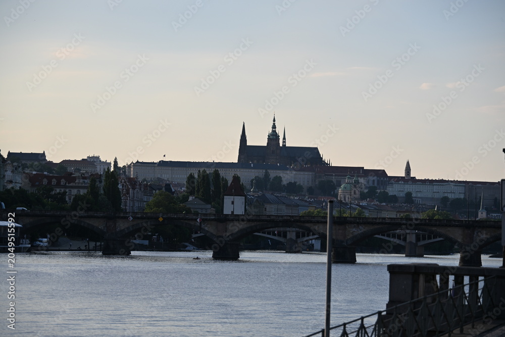 Fototapeta premium Vltava River with Stone Bridge and Prague Castle in the Background on a Sunny Day