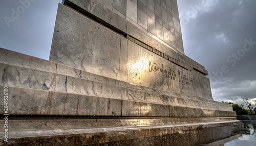 Marble monument with weathered inscriptions honoring fallen soldiers against a dramatic sky