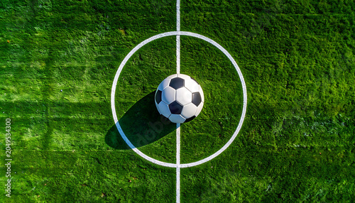 Soccer ball on green grass field center circle from aerial view, sport game concept