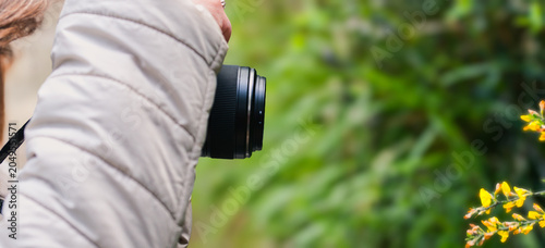 Tourist woman taking a photo with her camera in nature