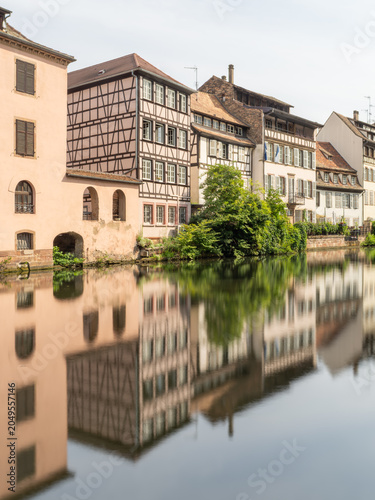 Historic riverside buildings reflected in tranquil canal of Strasbourg France