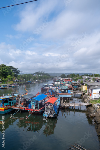 High-angle view of colorful traditional wooden fishing boats moored along a river canal in Cilacap, Indonesia.