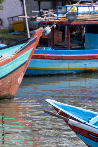 Traditional wooden fishing boats moored side by side in a harbor in Cilacap, Indonesia.