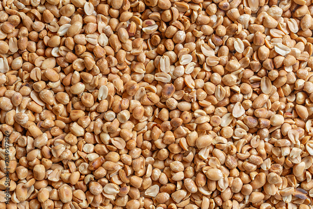 Fototapeta premium Top view of roasted peeled peanuts background texture.
