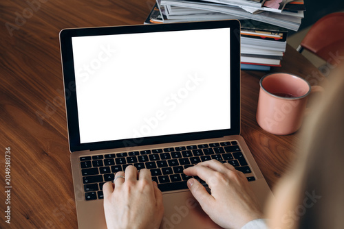 laptop mockup  Person typing on a laptop with a blank white screen, suggesting remote work, online communication, writing and productivity in a casual home workspace or freelance