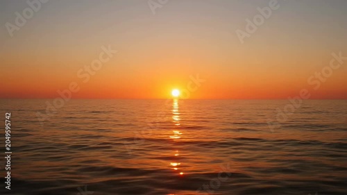 The sequence features a peaceful scene of the sun setting over a calm body of water