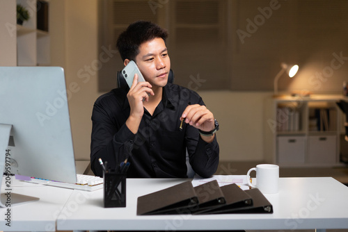 Businessman Talking on Phone at Desk Working Late in Modern Office With Computer and Files