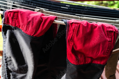 Vibrant red quality workwear pants drying on the clotheshorse on a sunny summer day.