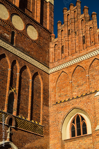 Detailed Red Brick Facade of a Historic Gothic Cathedral in the Warm Glow of Afternoon Sunlight, Highlighting Intricate Medieval Architectural Features
