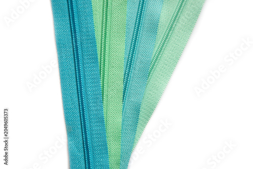 Collection of Vibrant Sewing Zippers in Teal, Aqua, and Green Tones, Ideal for Dressmaking, Tailoring, and Craft Projects, Isolated on White Background
