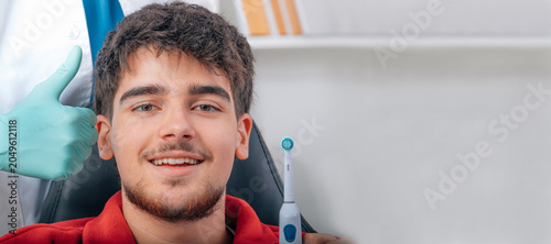 Slika na platnu Happy caucasian young man sitting in dental chair, smiling confidently while den