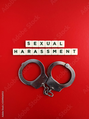 Handcuffs and sexual harassment scrabble tiles on red background