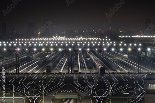 Railway Freight Yard at Night with City Skyline