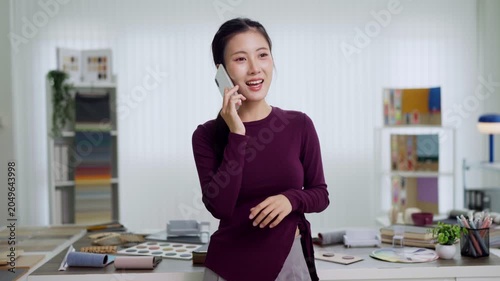 Asian furniture designer talking phone client consultation creative studio workspace interior design professional business communication call office