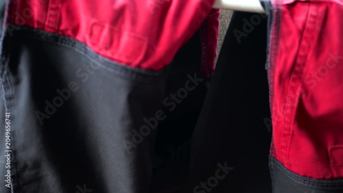 Slow pan shot, vibrant red quality workwear pants drying on the clotheshorse .