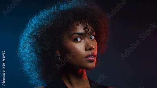 Young Woman With Curly Hair Posing Confidently In Dramatic Studio Lighting