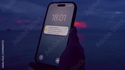 Close View of Smartphone Displaying Hurricane Warning Near Calm Ocean Before Tropical Storm, Emergency Notification, Cinematic Shallow Focus Evening Shot