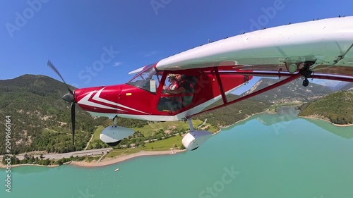 aerial footage, dynamic selfportrait of light airplane flying over turquoise lake in provence under blue sky
