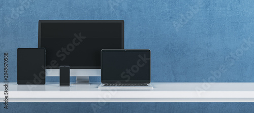 Modern digital device set featuring computer monitor, laptop, tablet and smartphone arranged on clean desk against textured blue background for technology branding. 3D Rendering