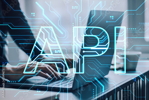 Hands typing on laptop with glowing API circuitry overlay in modern workspace...