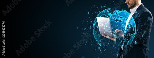 Business professional using laptop with digital globe and binary data around ...