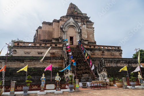 Canvas Print The ancient Wat Chedi Luang temple in Chiang Mai, Thailand, is adorned with colorful flags and guardian statues, inviting visitors to explore its historic grounds