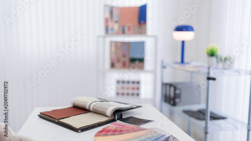 interior designer workspace with fabric samples color swatches material selection for furniture design project at modern home office desk decorating planning