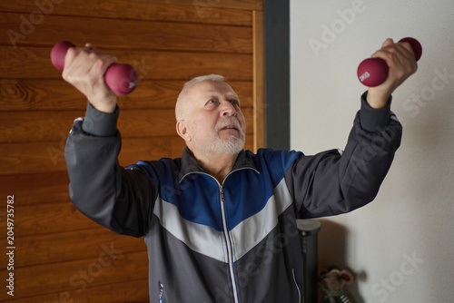 Photos Senior man exercises indoors, lifting weights to maintain fitness and vitality i