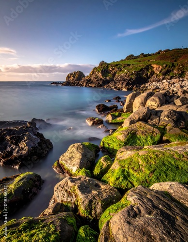 Mossy rocks on serene ocean shoreline.