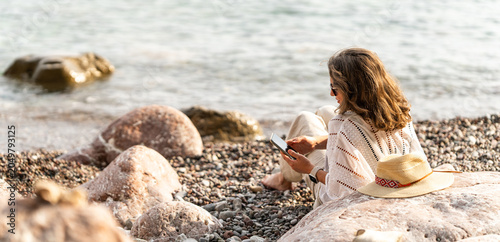 Woman using smartphone on the sea coast at summer