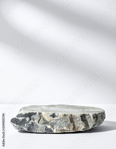 Empty rocky stone podium for product presentation, isolated on white background, minimal composition, centered stone pedestal. Close-up.