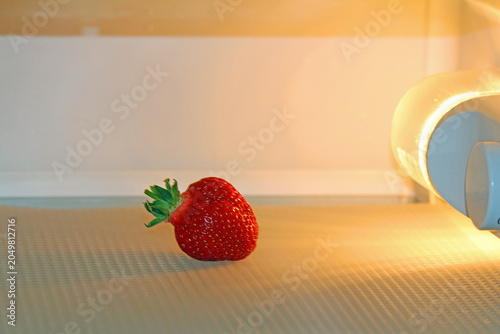 Fotografia one ripe strawberry in the refrigerator