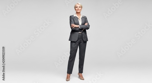 Confident Businesswoman Standing Arms Crossed in Gray Suit, Studio Portrait